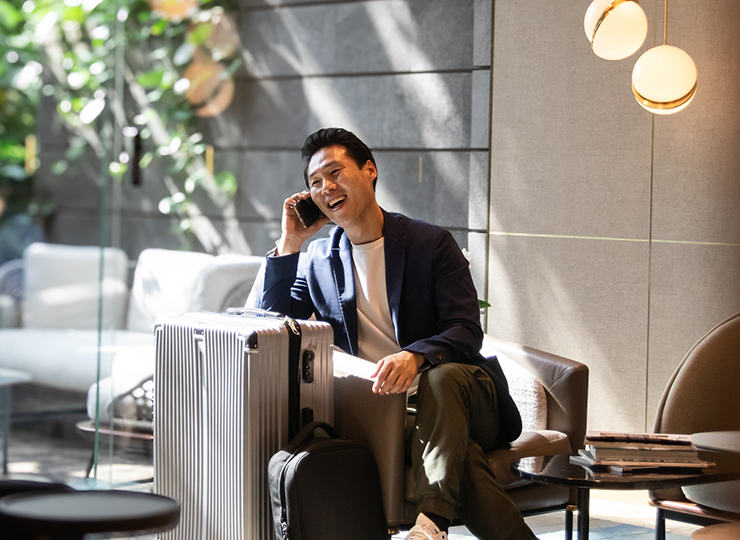 A business traveler sitting in an office lobby with their luggage