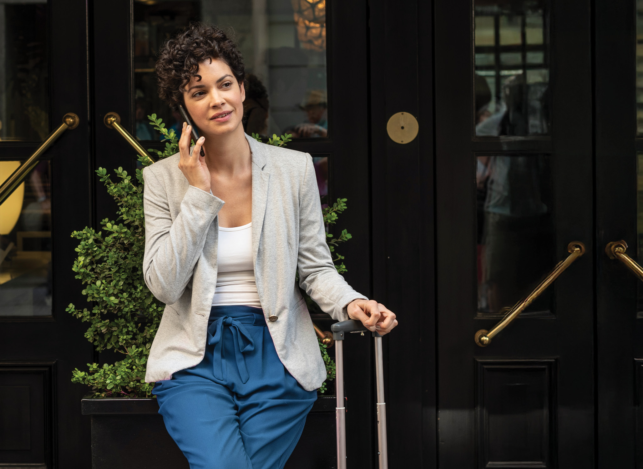 Business women sitting outside a hotel with her luggage