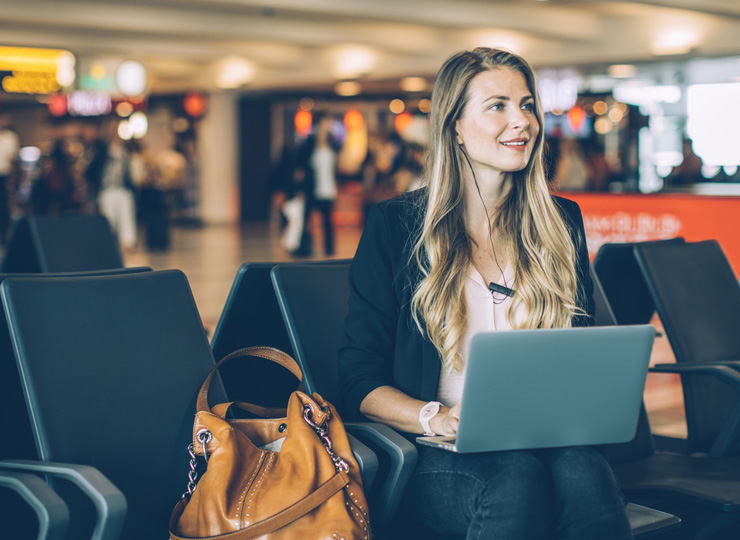 Business women in airport sitting with her laptop