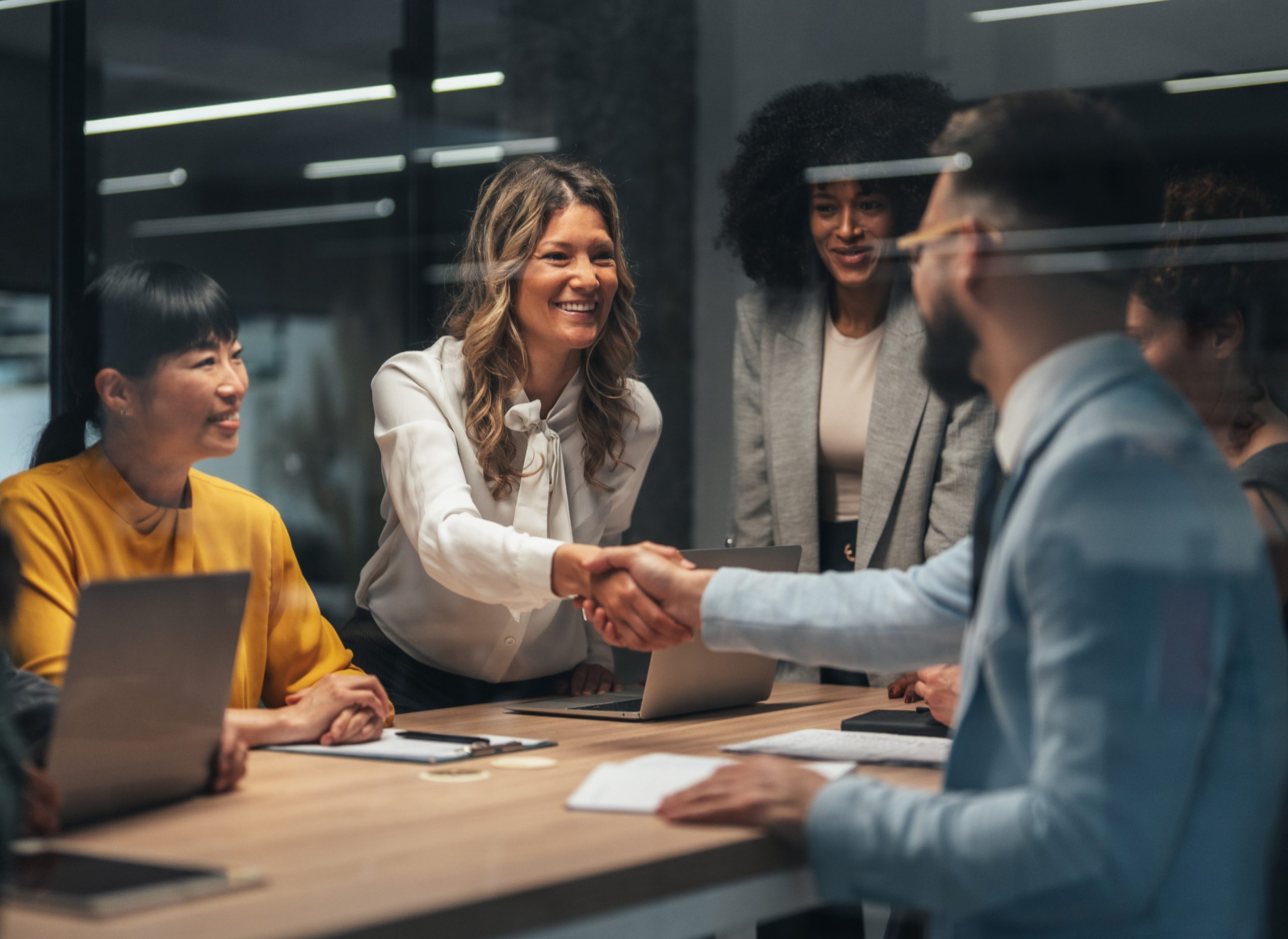 Business people in a board room discussing managed travel for SMEs shaking hands