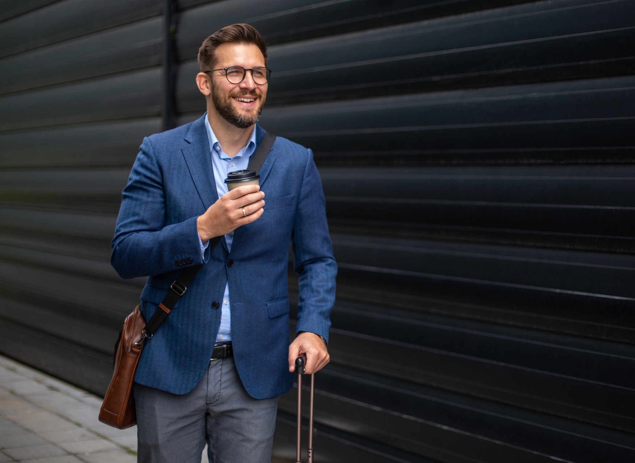 Male business traveler with suitcase and mobile phone in his hand