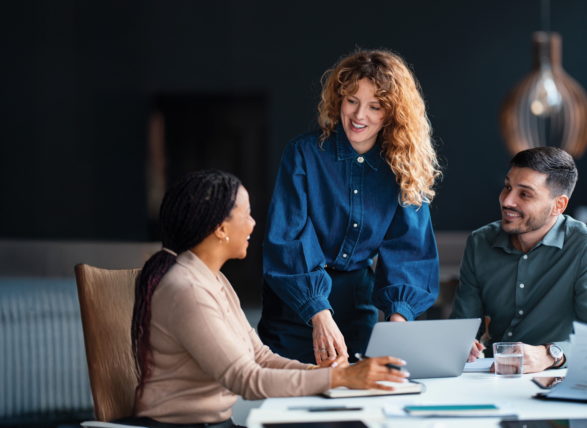 Three procurement professionals sitting in a meeting discussing the travel program